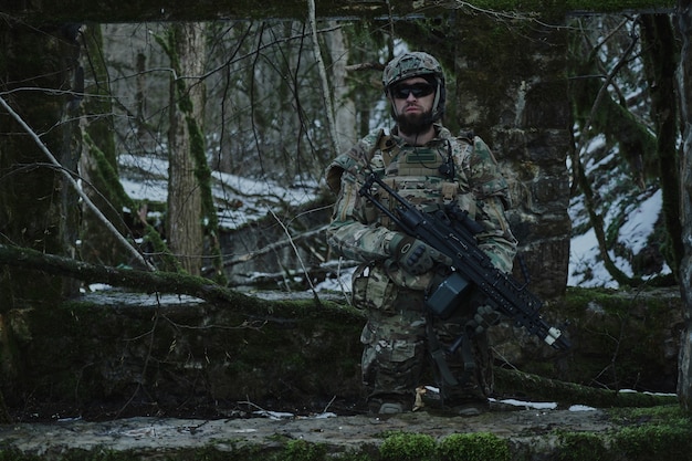 Portrait de joueur d'airsoft en équipement professionnel avec mitrailleuse dans la forêt. Soldat avec des armes en guerre