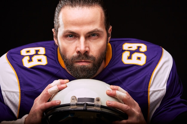 Portrait de joueur de football américain avec casque à la main gros plan sur fond noir