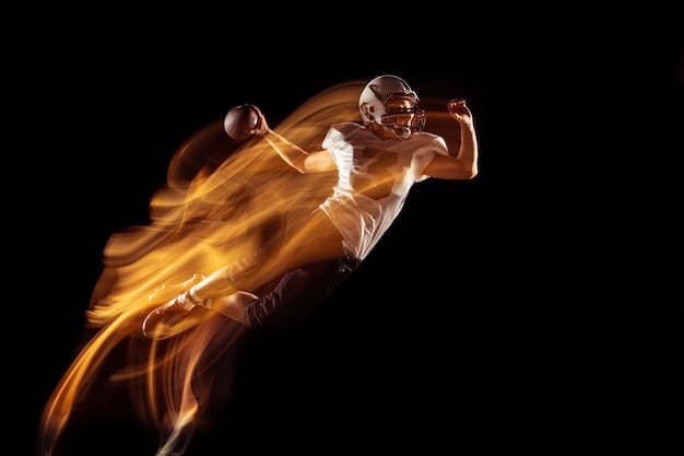 Portrait de joueur de football américain en équipement sportif isolé sur fond de studio sombre.