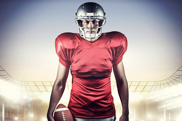 Portrait de joueur de football américain tenant le ballon contre le stade de rugby