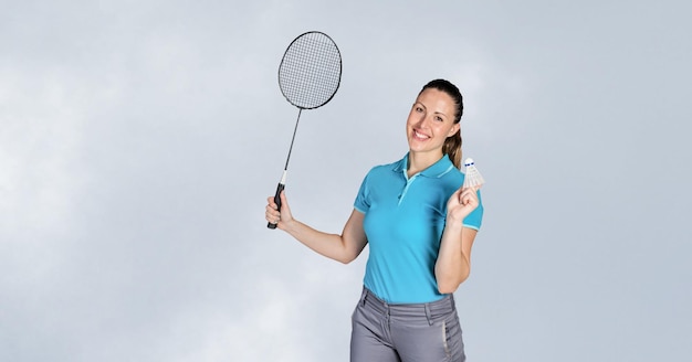 Portrait d'une joueuse de badminton caucasienne tenant une raquette souriante sur fond gris