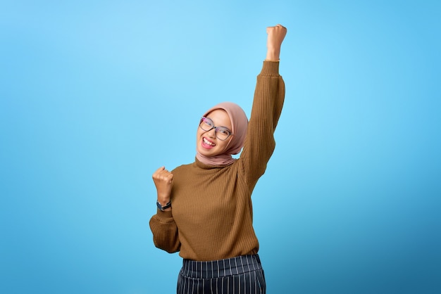 Portrait de joyeuse belle femme asiatique se réjouissant de célébrer la chance sur fond bleu