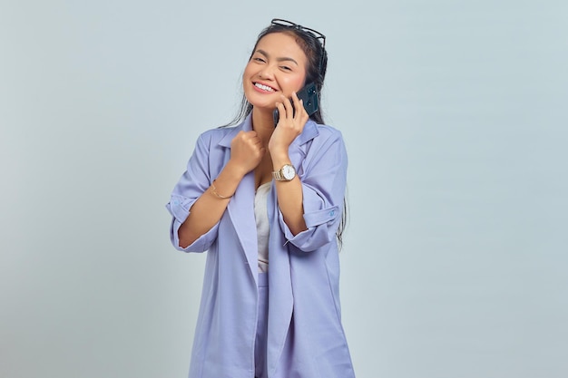Portrait de joyeuse jeune femme asiatique parlant à des collègues sur mobile isolé sur fond blanc