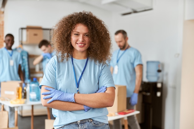 Photo portrait de joyeuse jeune femme bénévole en uniforme bleu souriant à la caméra en se tenant debout