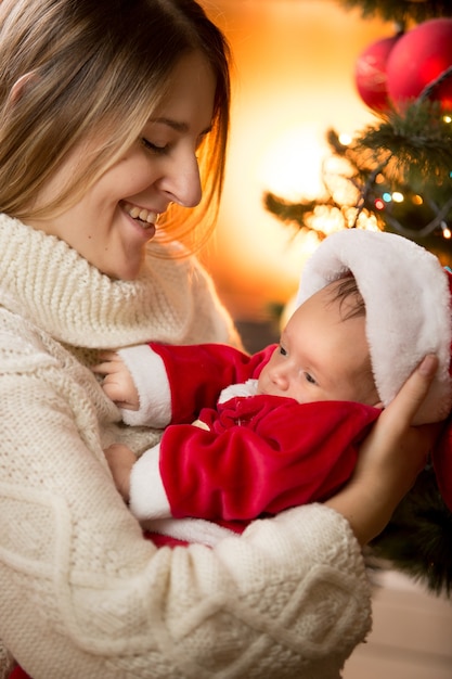 Portrait de joyeuse jeune mère et bébé garçon posant à la cheminée