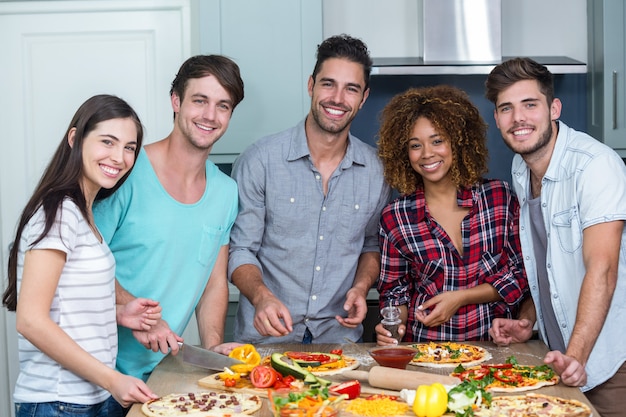 Portrait de joyeux amis multiethniques préparant une pizza à la maison