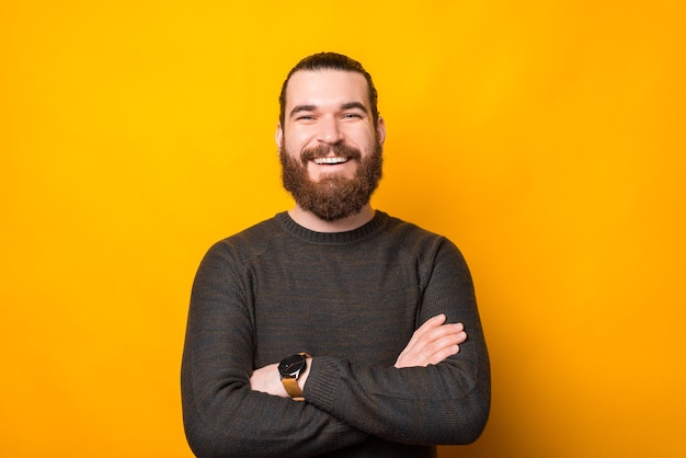 Portrait de joyeux bel homme barbu avec les bras croisés à la confiance à la caméra