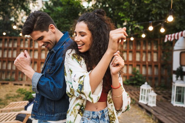 Portrait de joyeux couple homme et femme souriant tout en dansant ensemble près de la maison sur roues à l'extérieur