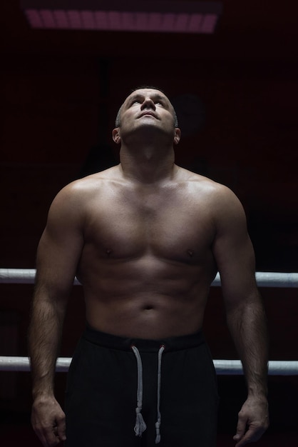 portrait d'un kickboxeur professionnel musclé qui se tient sur le ring tout en s'entraînant pour le combat