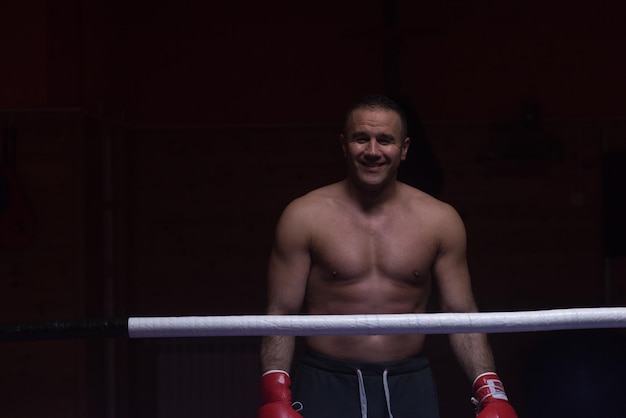 portrait d'un kickboxeur professionnel musclé qui se tient sur le ring tout en s'entraînant pour le combat