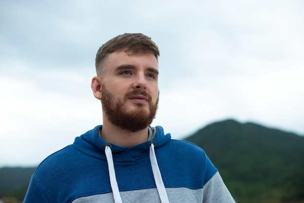 Portrait latéral d'un beau barbu sérieux pensif et pensif jeune homme sur fond de montagne naturel pensant rêver