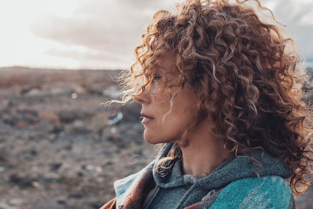 Portrait latéral d'une femme aux longs et beaux cheveux bouclés regardant devant elle, profitant d'une activité de loisirs en plein air