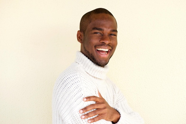 Photo portrait latéral d'un homme afro-américain séduisant en pull souriant sur fond clair