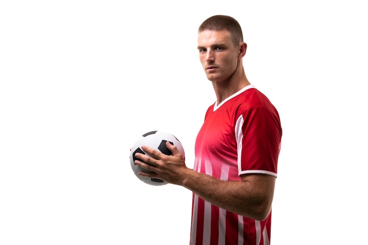Photo portrait latéral d'un joueur de football caucasien confiant tenant le ballon sur un fond blanc