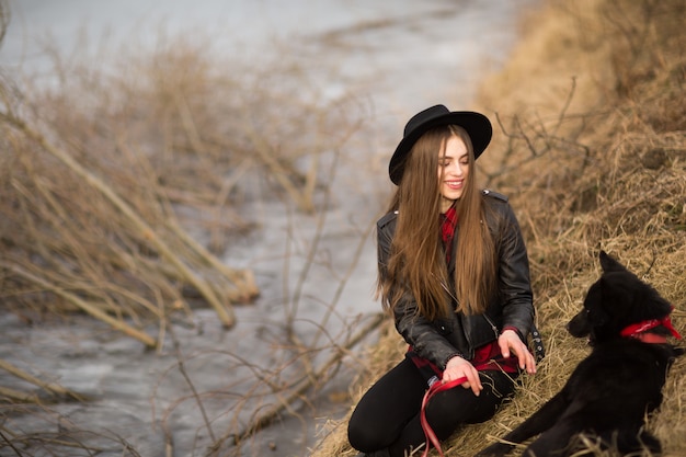 Portrait lifestyle de la jeune femme au chapeau noir avec son chien