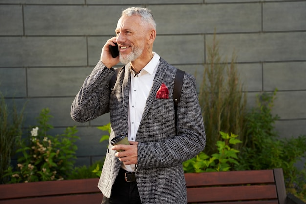 Portrait en ligne d'un homme d'affaires d'âge moyen heureux et prospère en costume élégant souriant tout en