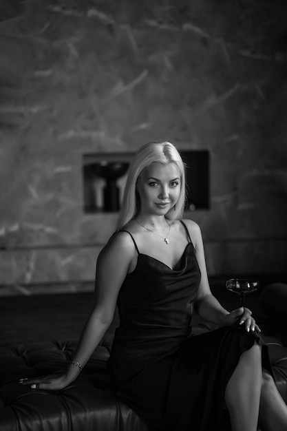 Portrait d'une luxueuse jeune femme blonde vêtue d'une robe sexy noire Dans un intérieur sombre