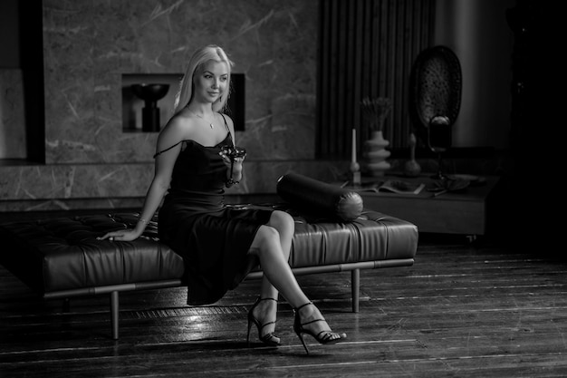 Portrait d'une luxueuse jeune femme blonde vêtue d'une robe sexy noire Dans un intérieur sombre