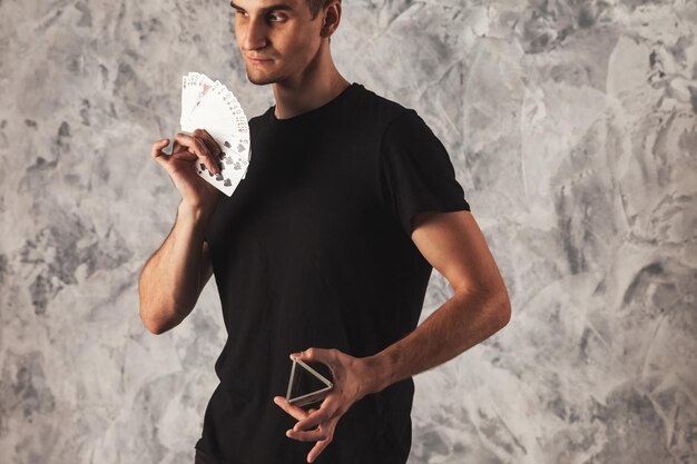 Portrait magicien avec des cartes de jeu sur fond de mur gris