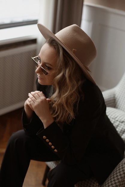 Portrait d'un magnifique modèle féminin avec un maquillage parfait portant un chapeau à la mode et des lunettes de soleil à la mode