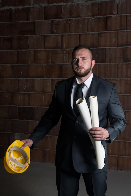 Portrait de maître de construction avec casque jaune et plan dans les mains