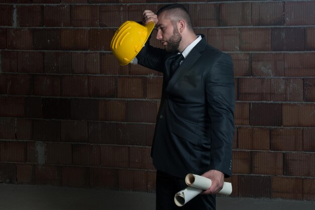 Portrait de maître de construction avec casque jaune et plan dans les mains