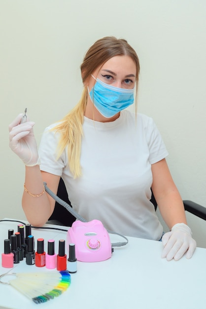 portrait d'un maître de manucure dans le salon sur le lieu de travail avec des outils dans ses mains