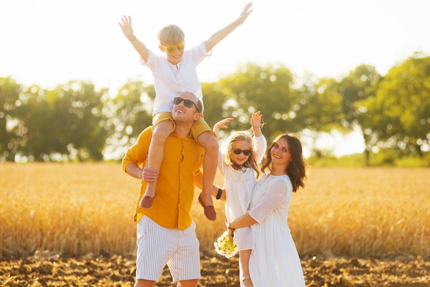 Portrait de maman et papa portant fille et fils rire ensemble sur un champ.