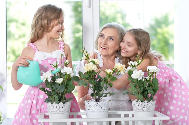 Portrait d'une mamie avec ses petites-filles arrosant des fleurs