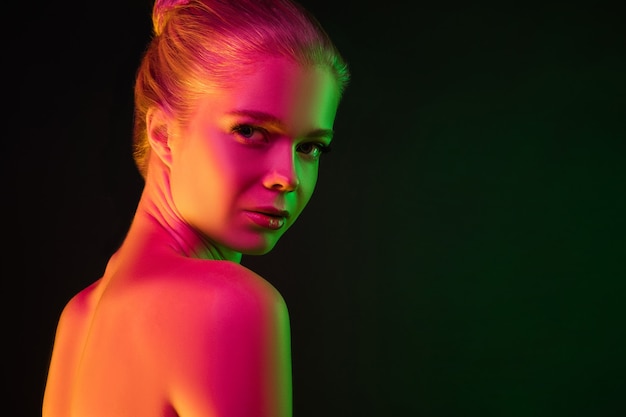 Portrait de mannequin féminin en néon sur fond de studio sombre.