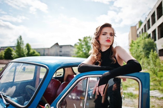 Portrait de mannequin fille belle avec un maquillage lumineux dans un style rétro se pencha sur une porte de voiture vintage.