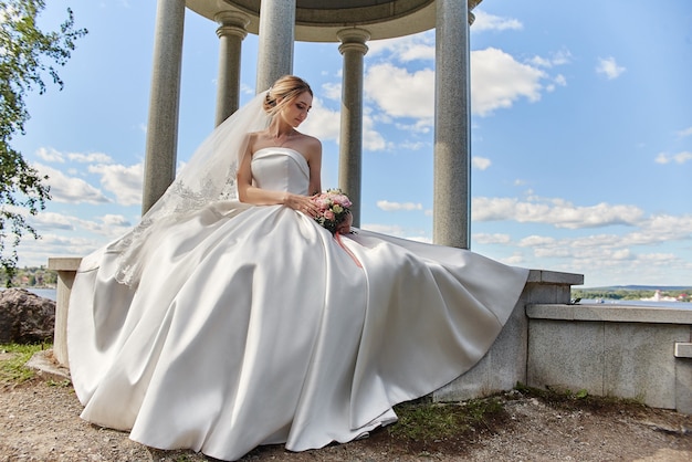 Portrait de mariage d'une femme mariée sous un voile blanc. Une fille en robe de mariée tenant un bouquet de fleurs dans ses mains