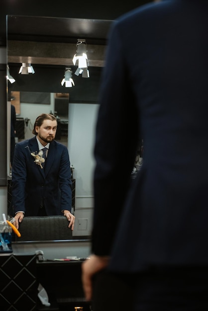 Portrait d'un marié masculin dans un costume bleu dans le salon de coiffure du matin