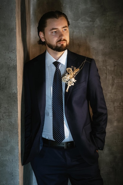 Portrait d'un marié masculin dans un costume bleu dans le salon de coiffure du matin