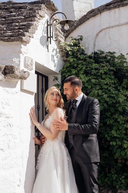 Portrait de mariée blonde en robe blanche et marié brun en costume s'embrassant et se regardant