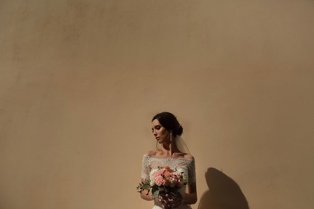 Portrait de la mariée avec un bouquet de fleurs sur le fond du mur