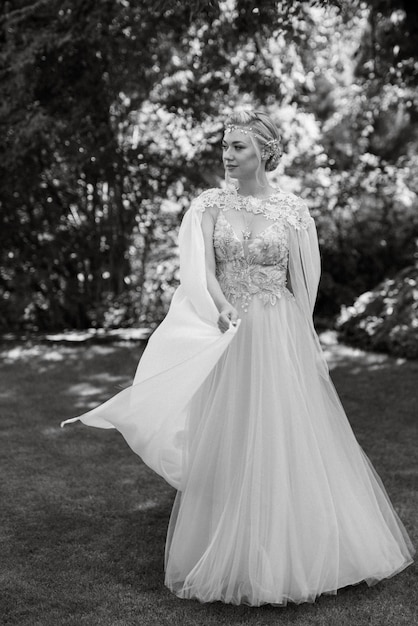 Photo portrait d'une mariée heureuse dans une robe légère sur une prairie verte dans le parc portant des accessoires d'elfes