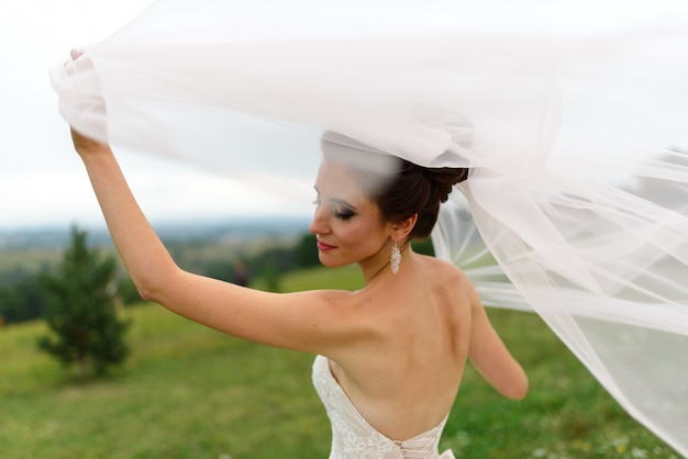 Portrait d'une mariée sous un voile. Le vent fait exploser un voile. Une femme est debout avec son dos. Fermer