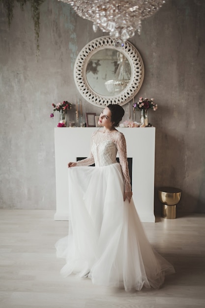 Portrait de mariée vêtue d'une robe de mariée de mode avec des plumes avec un maquillage et une coiffure de luxe