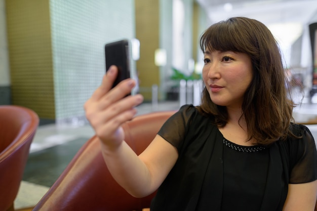 Photo portrait de mature belle femme japonaise se détendre à l'intérieur du café