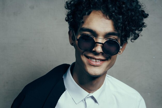 Portrait d'un mec aux cheveux bouclés heureux dans un costume classique et des lunettes