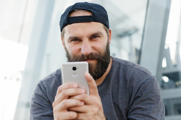 Portrait d'un mec à barbe. Souriant bel homme écrivant un message au téléphone