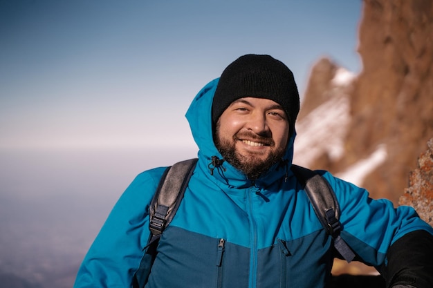 Portrait d'un mec avec une barbe en vêtements d'hiver sur fond de montagnes