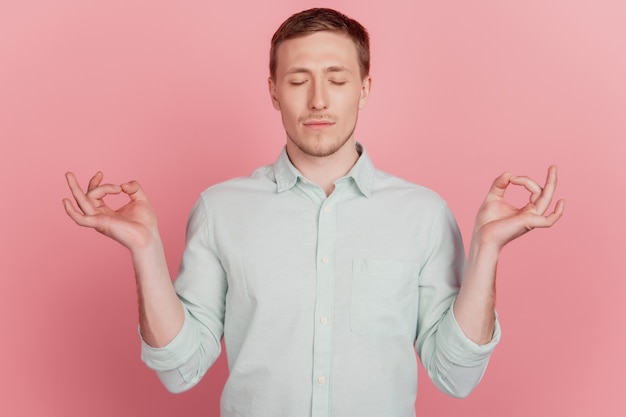 Portrait d'un mec concentré en bonne santé et concentré tenir les doigts fermer les yeux méditer sur fond rose