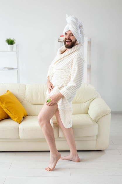 Portrait d'un mec gai portant une serviette turban se fait un massage avec une brosse de massage. Soins de la peau masculine et concept de spa
