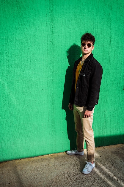 Portrait d'un mec habillé moderne dans la rue avec des lunettes de soleil.