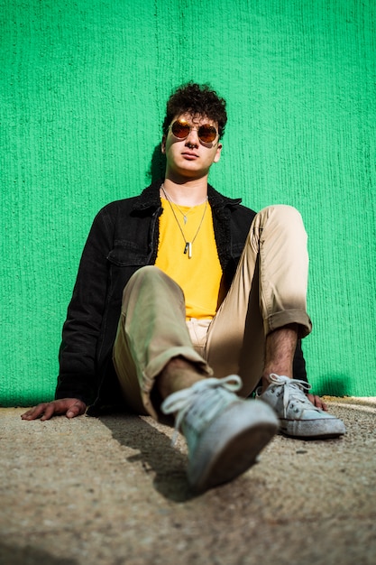 Portrait d'un mec habillé moderne dans la rue avec des lunettes de soleil.