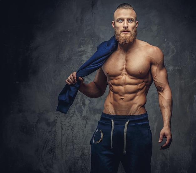 Portrait de mec musclé avec barbe en pantalon de sport bleu isolé sur fond gris.