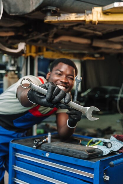 Photo portrait d'un mécanicien africain en uniforme au poste de réparation de voitures