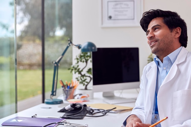 Portrait d'un médecin ou d'un généraliste portant un manteau blanc au bureau au bureau